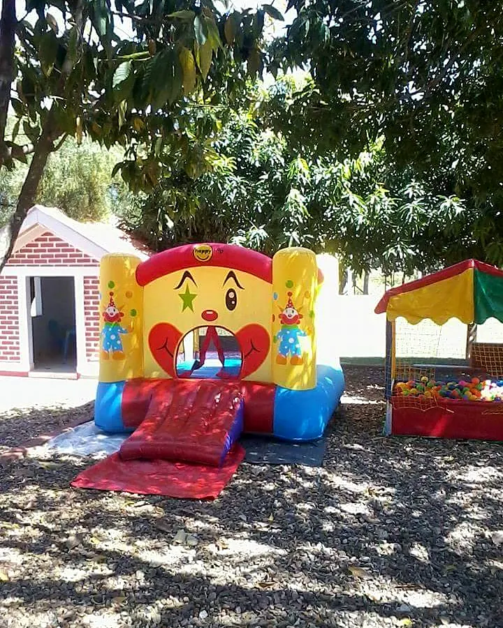 Pula-pula de palhaço e piscina de bolinhas montados em um quintal