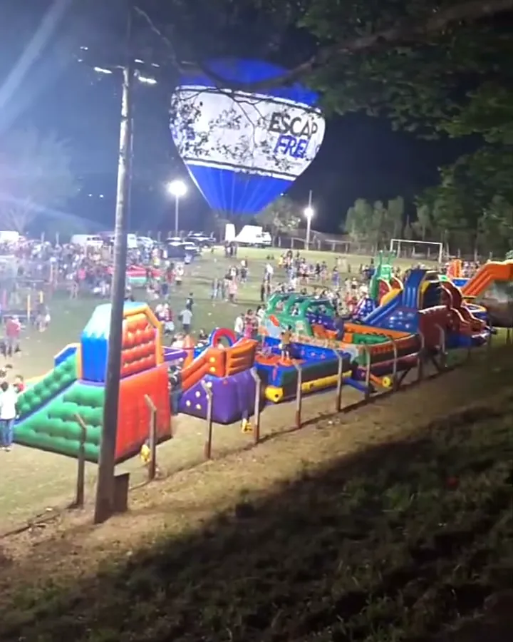Festa noturna de Dia das Crianças com vários brinquedos infláveis iluminados em um campo